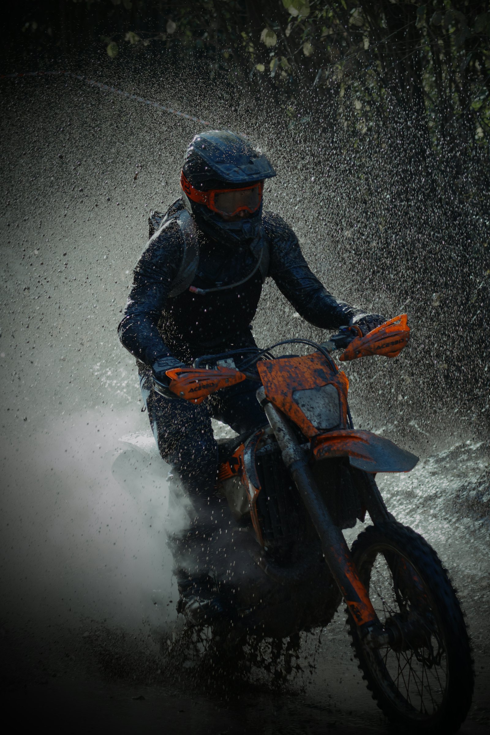 Moto d'enduro légère franchissant une flaque sur une piste