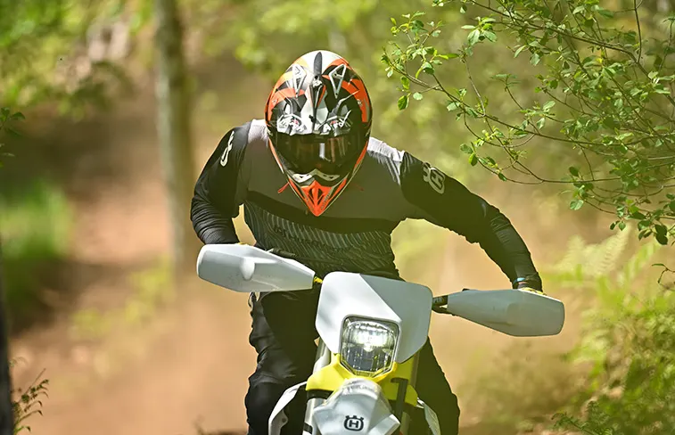 Pilote lancé vers la caméra sur un single en forêt