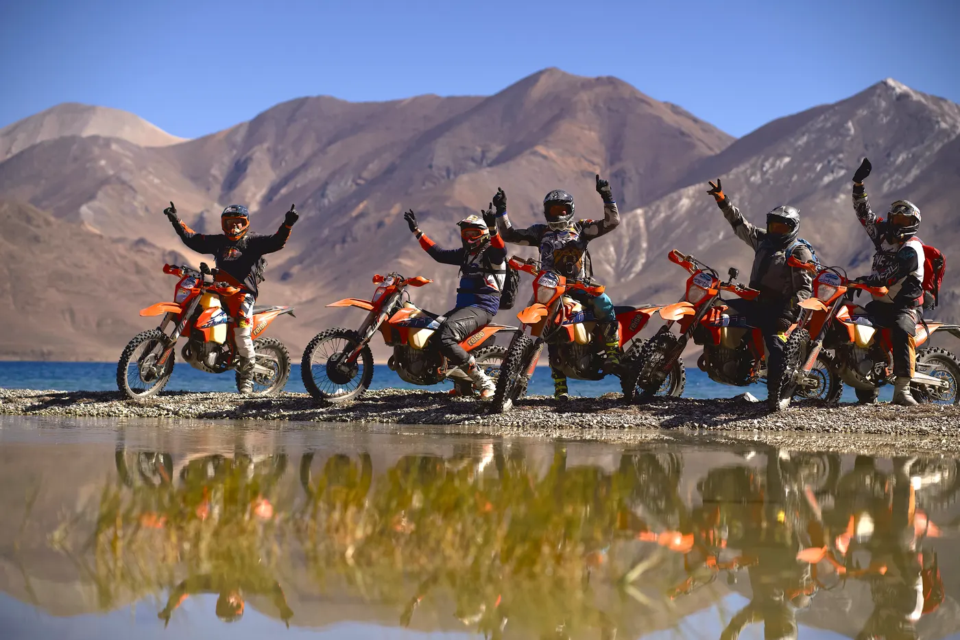 Groupe de pilotes bras levés, reflet dans un lac de montagne