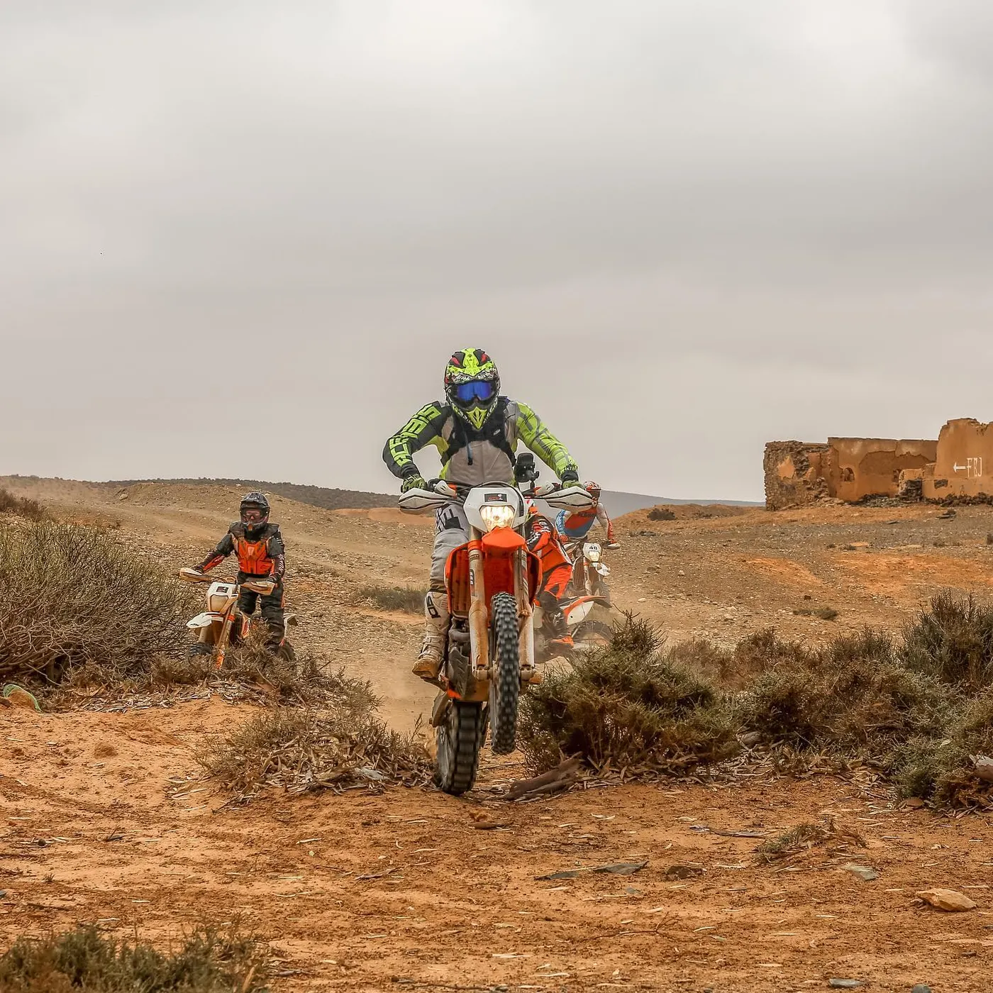 Pilote face caméra sur piste désertique, kasbah en ruine