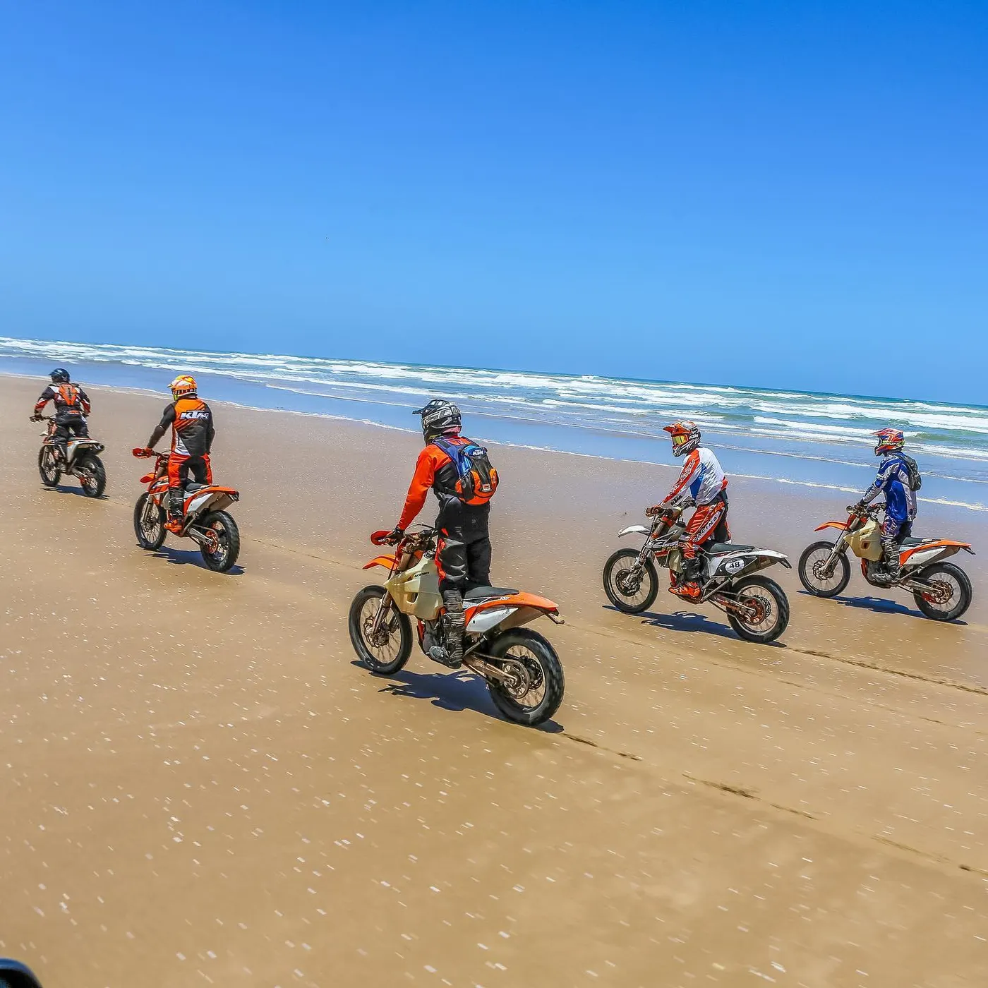 Groupe de pilotes roulant sur la plage, vagues de l'Atlantique