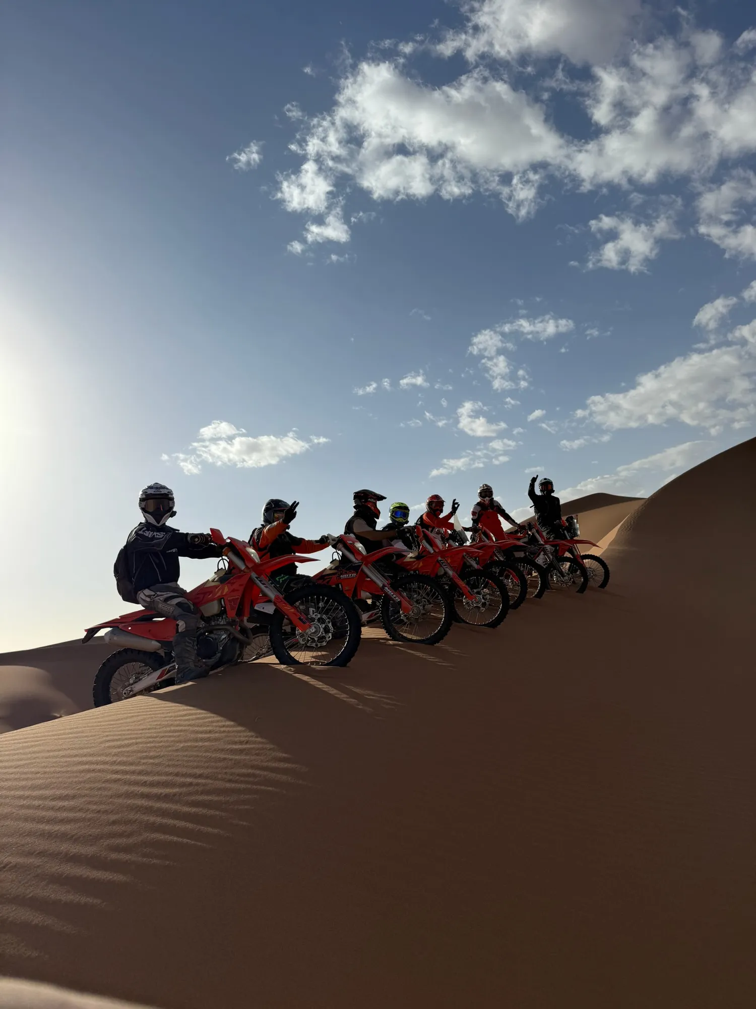 Groupe de pilotes aligné sur une crête de dune au coucher du soleil