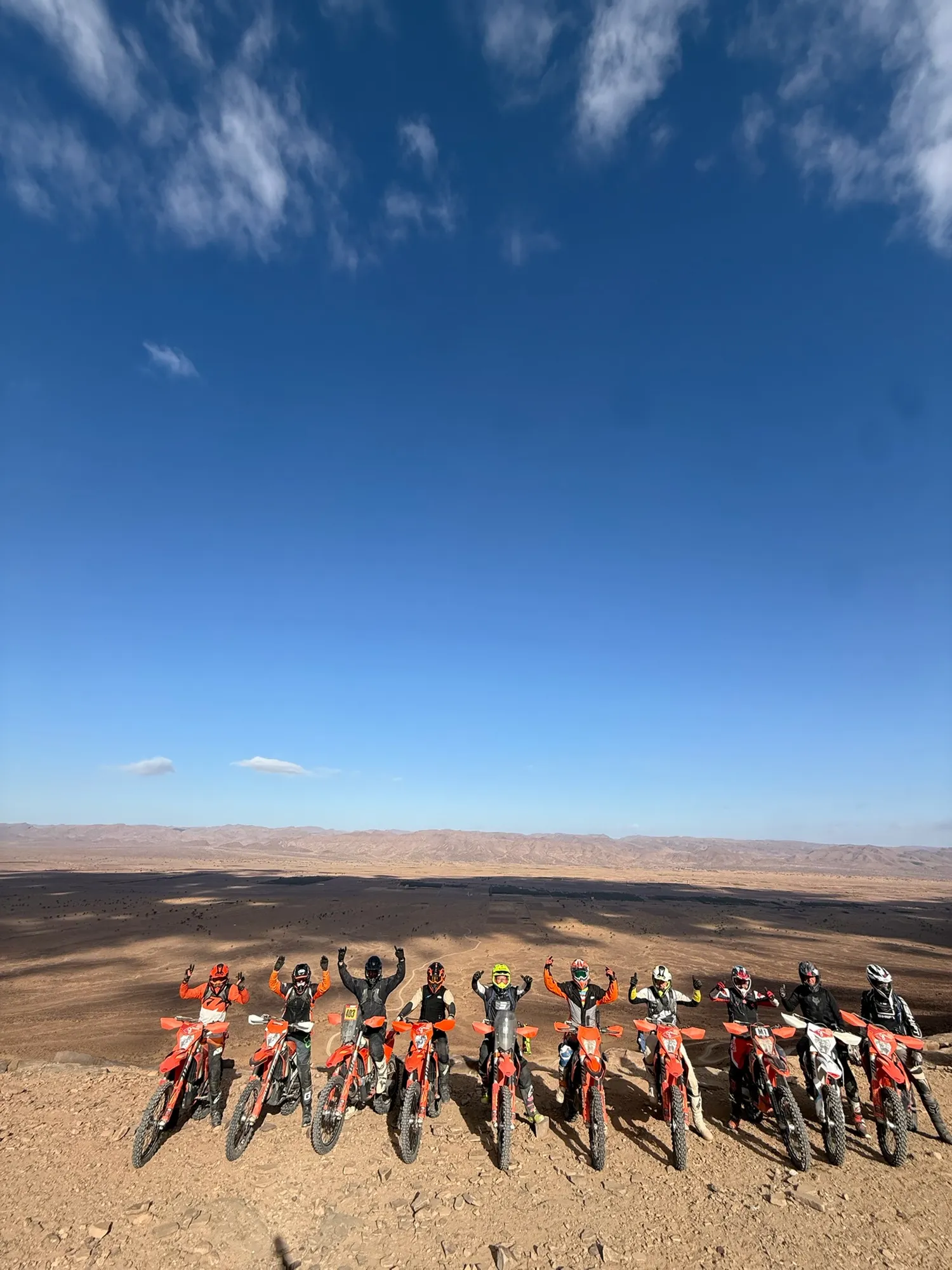 Groupe de pilotes bras levés sur un plateau, désert à perte de vue
